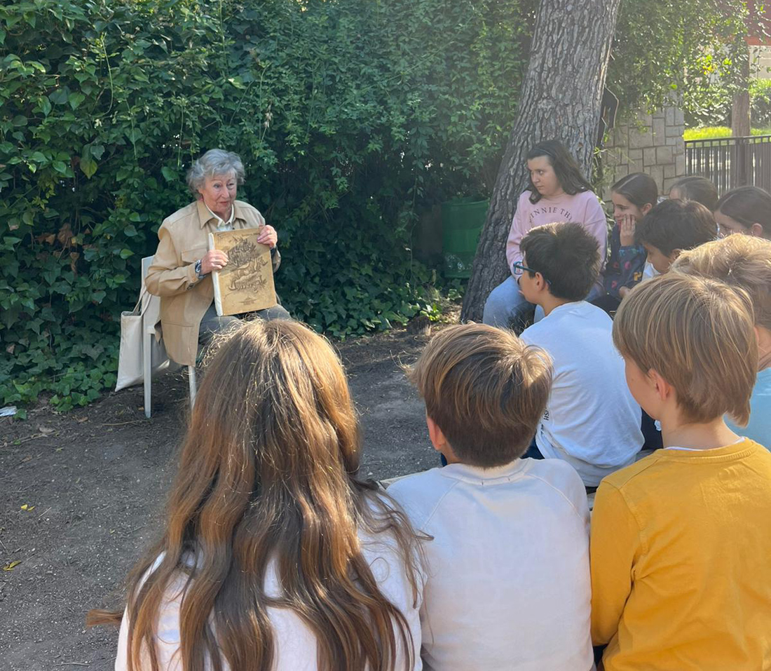 Una señora mayor cuenta una historia a un corro de niños que escuchan atentamente