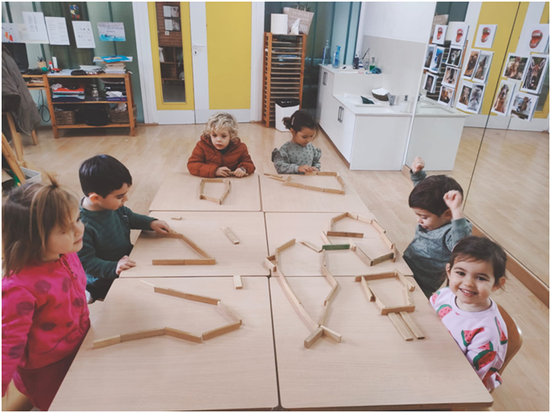 Niños sentados en mesa dibujando ballenas con material Kapla