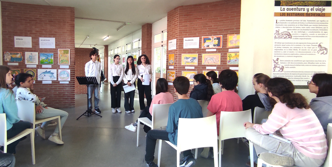 Cuatro alumnos de 2º ESO del Centro Educativo Gençana, de pie, presentan a sus compañeros de 1º ESO la exposición "Los bestiarios medievales", en que han representado animales mitológicos, dentro del proyecto "La aventura y el viaje"