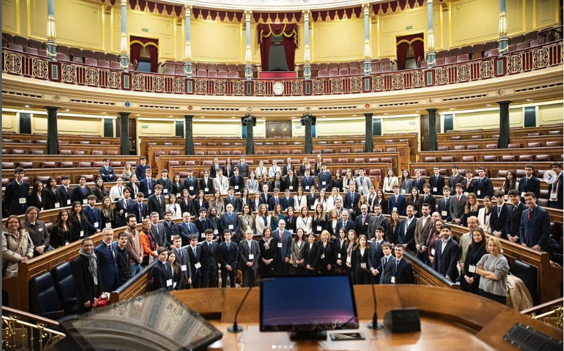 Foto de grupo de los jóvenes estudiantes de Secundaria y Bachillerato de toda España participantes en la fase nacional del concurso Modelo Parlamento Europeo. Posan en los escaños del Congreso de los Diputados.