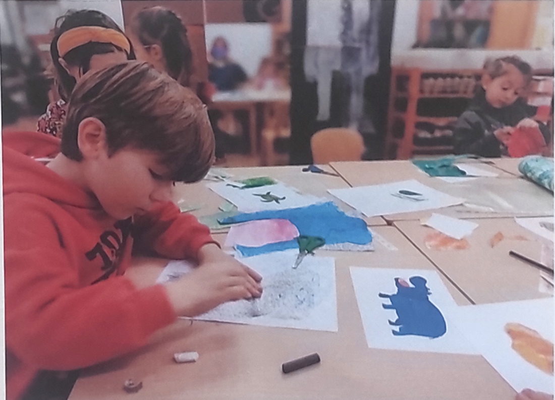 Niño de 4 años dibuja un hipopótamo al estilo Eric Carle en su pupitre del colegio