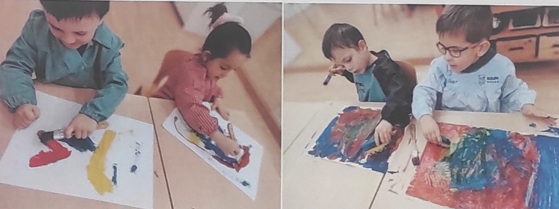 Cuatro niños de cuatro años pintan en diferentes colores 