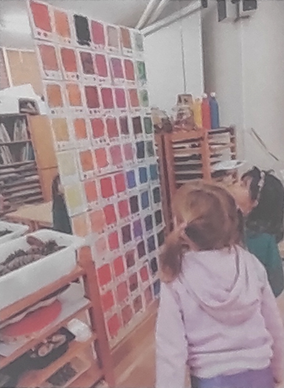 Dos niñas contemplan el pantone de colores que han creado, que se encuentra frente a ellas ordenado por tonalidades