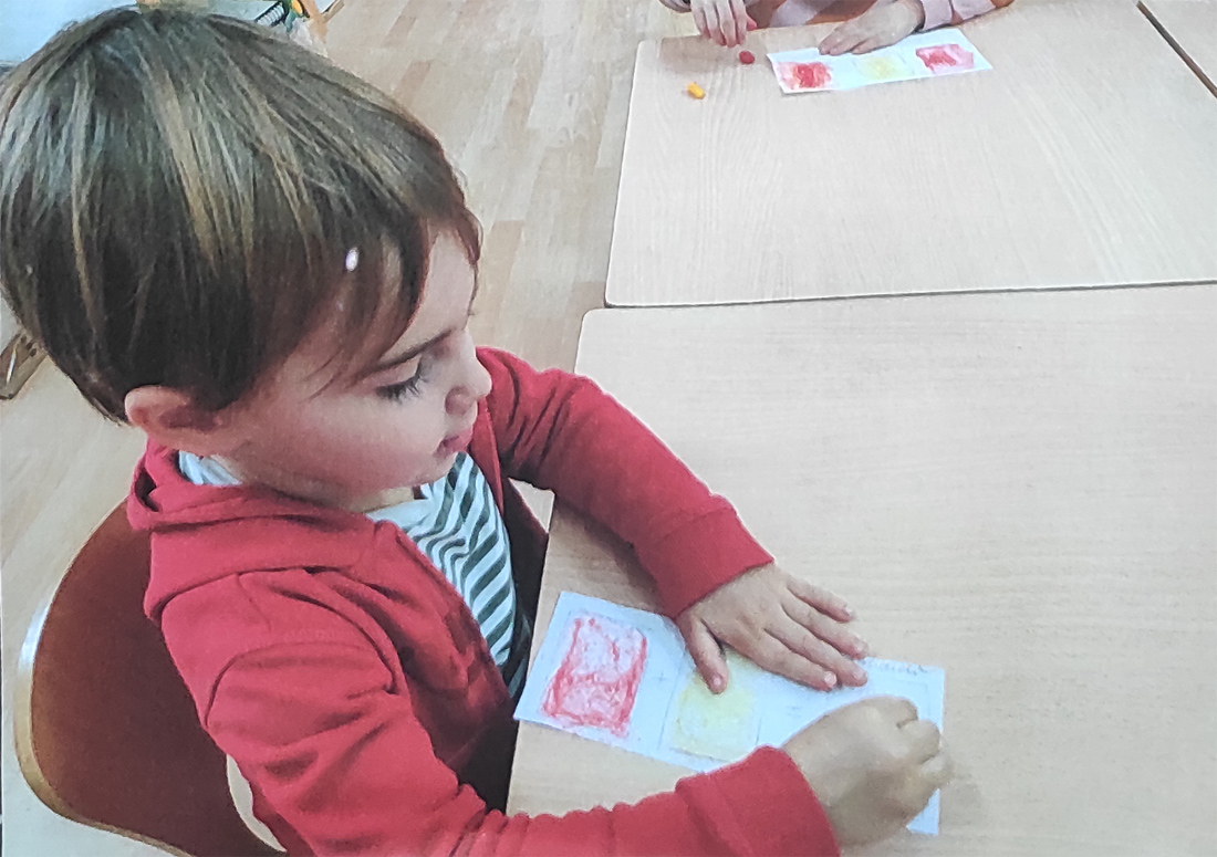 un niño, que aparece de perfil, pinta en un folio
