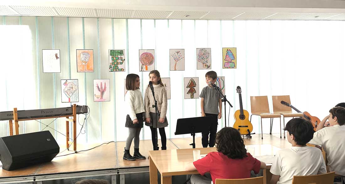 Tres alumnos de Gençana subidos a un escenario recitando poesía